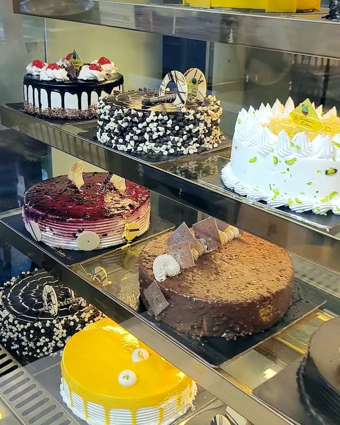 A glass display counter holding eight different iced cakes